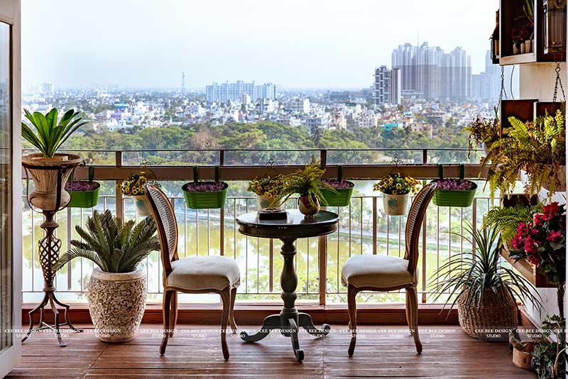 A balcony adorned with a table, chairs, and potted plants, creating a serene outdoor space.