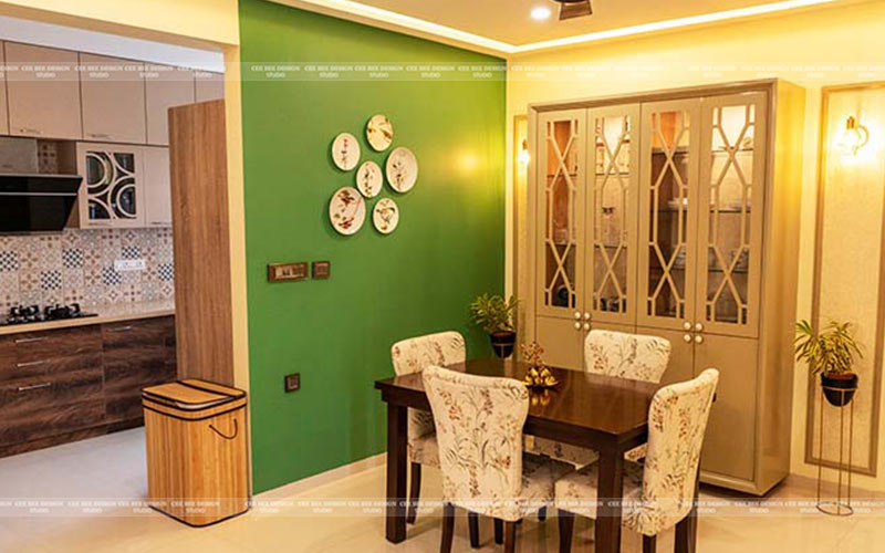 a small dining table with chair and a green wall behind