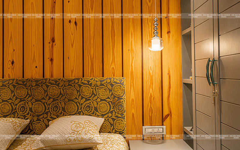 Bed with yellow and white bedspread against wood wall pallet.