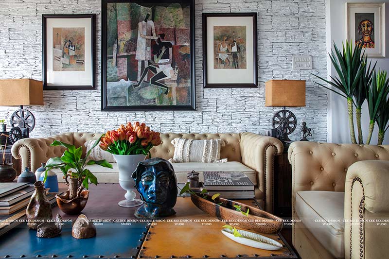 A cozy living room with a couch, coffee table, and paintings on the wall.