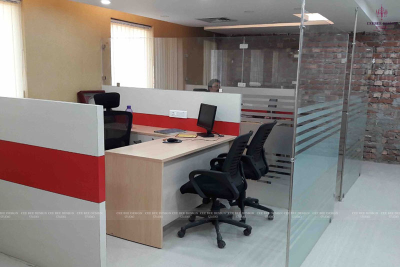 a striking office interior design featuring a glass wall and vibrant red desks.