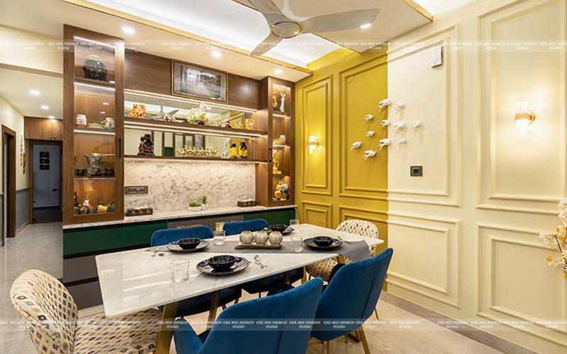 dining space with yellow colour designing wall and dining table and chairs with house decorative objects in selves