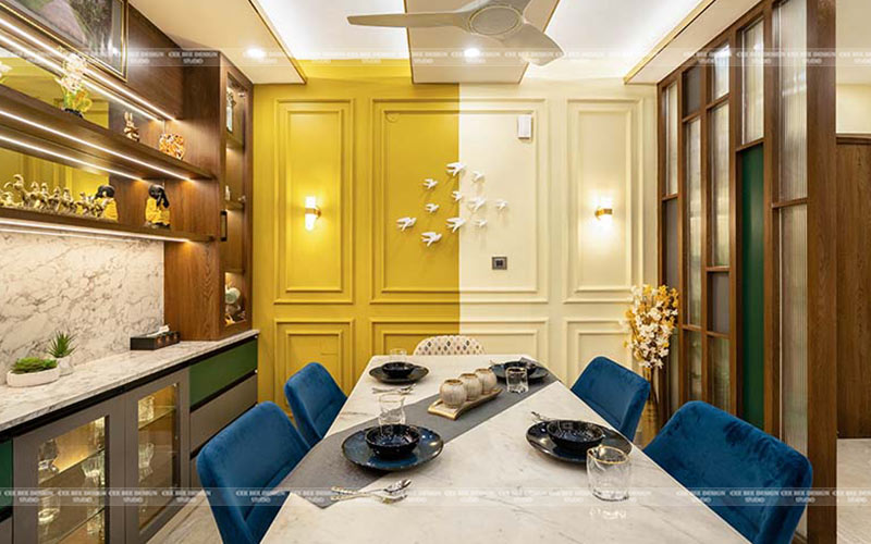Dining room with yellow walls and blue chairs, creating a vibrant and inviting atmosphere.
