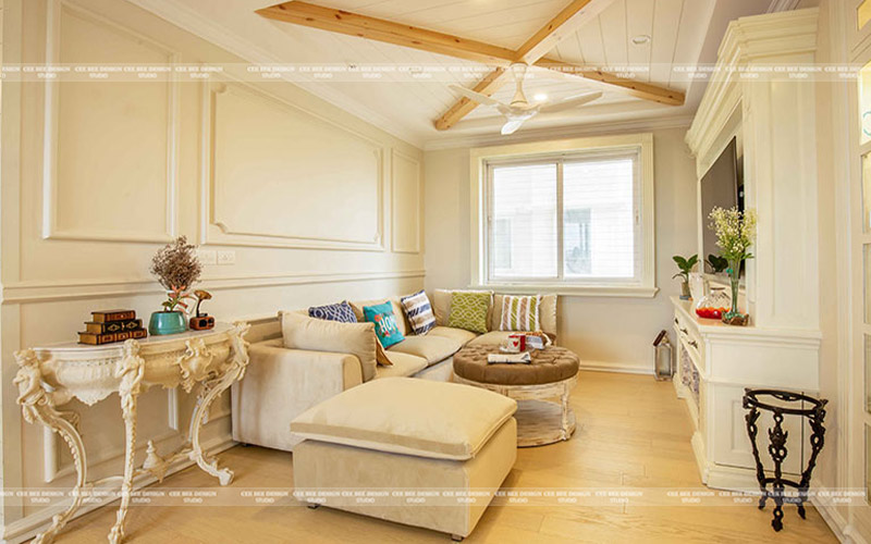 A modern living room with white furniture and wooden beams, creating a cozy and elegant atmosphere.