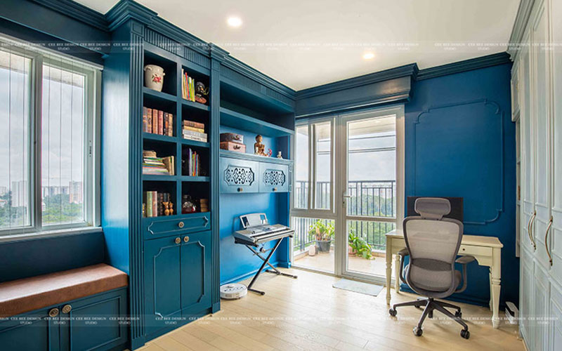 A blue home office with a desk and bookshelf.