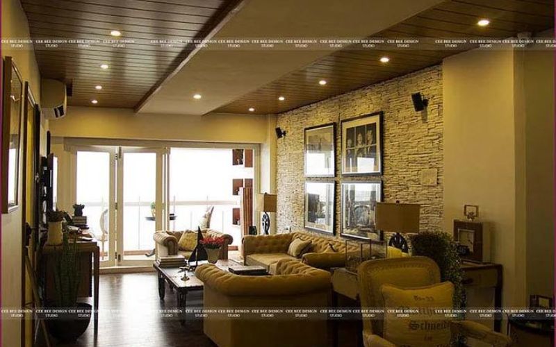 living room textured wall with oft furniture and table in middle and balcony with natural light entering the room