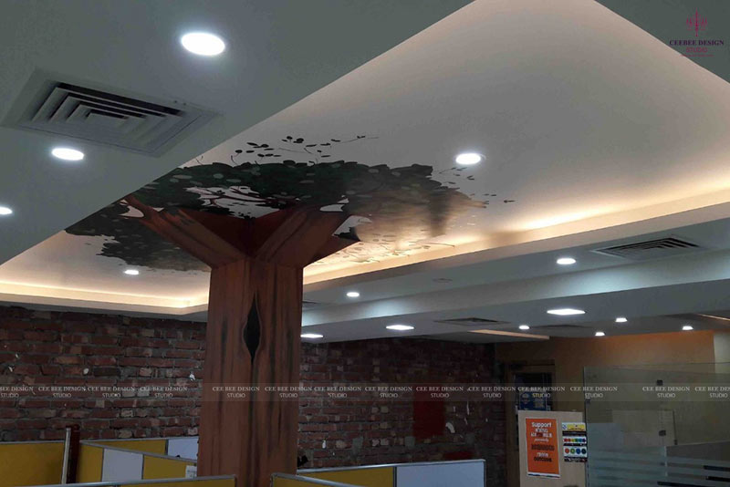 a creatively designed office with an artistic tree painting on the ceiling.